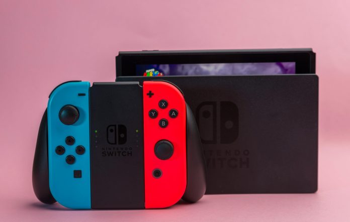 a nintendo switch is docked in the background while a joycon controller sits in the foreground - its handles are red and blue